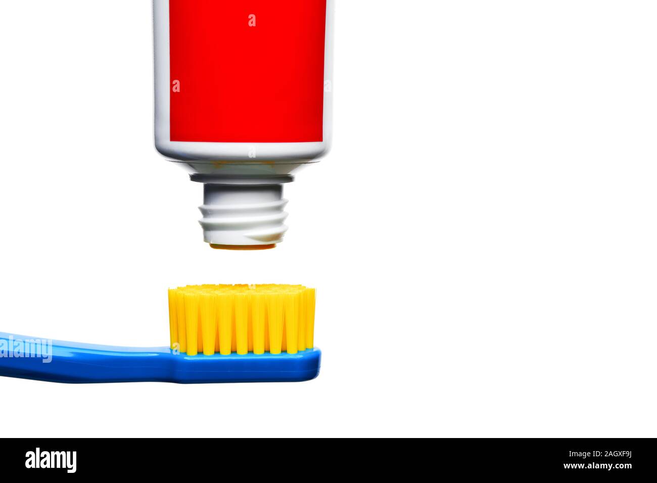 Toothpaste tube ready to squeeze is over the top of a toothbrush