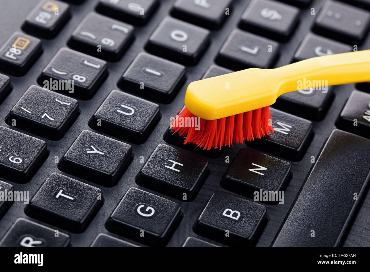 Keyboard cleaning with a toothbrush. Dust and germ free keyboard Stock Photo