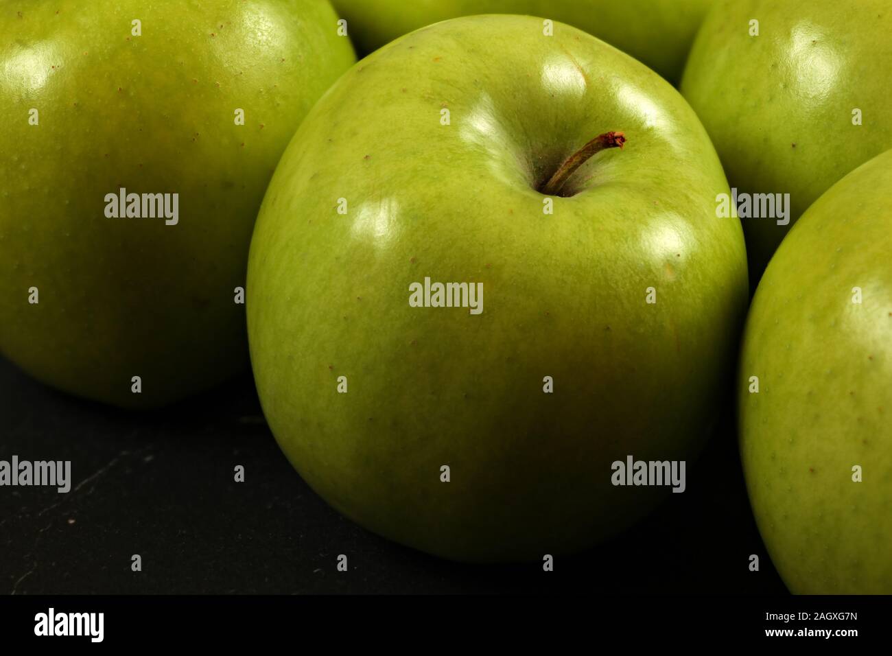 Closeup of green apples on black board, detailed photo - texture on apple skin visible. Stock Photo