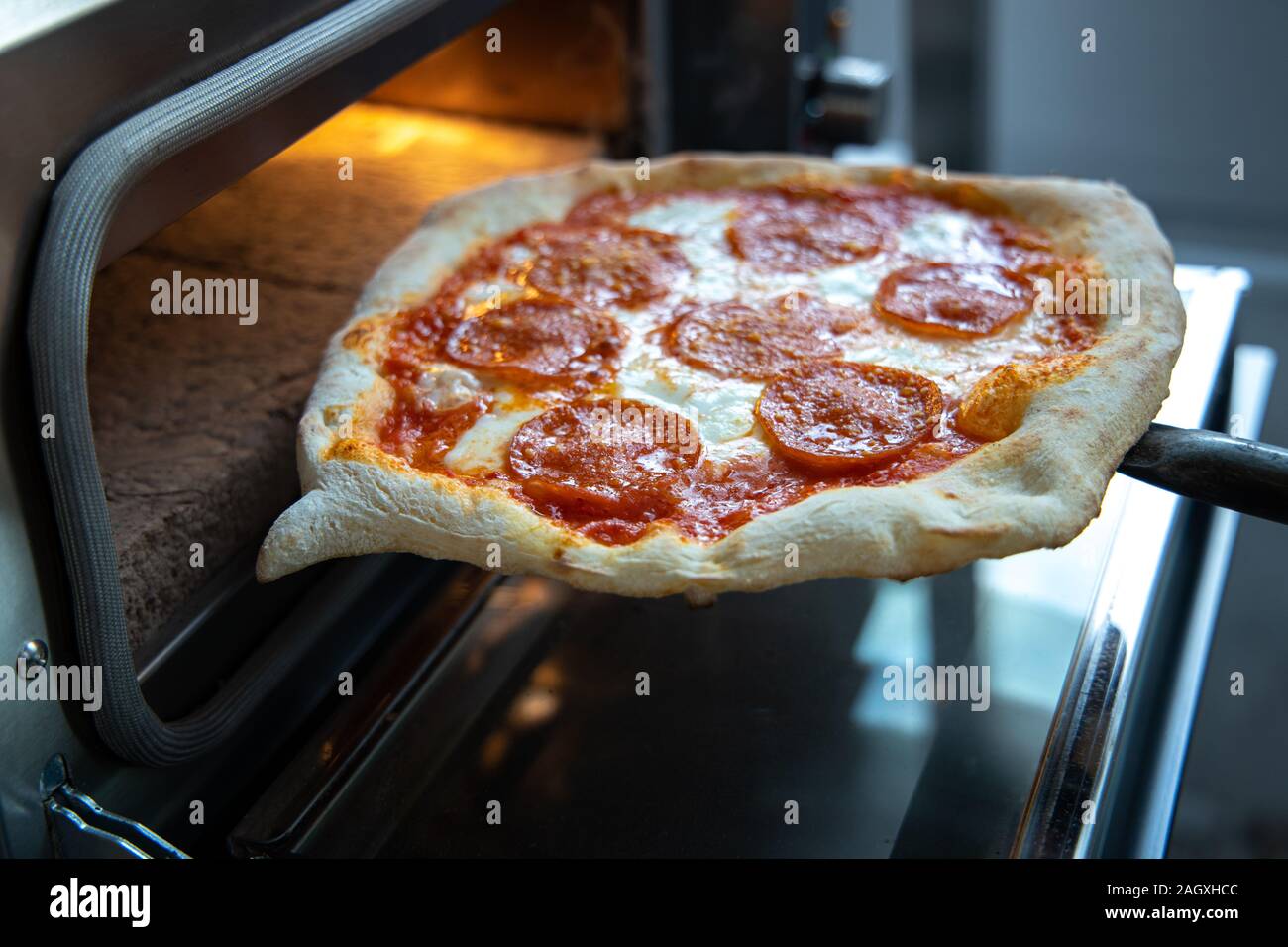 Putting pizza in oven at restaurant kitchen Stock Photo Alamy
