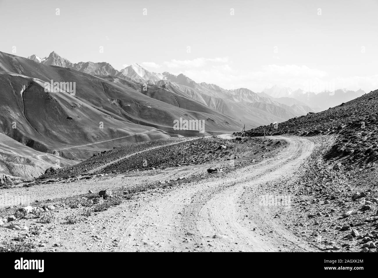 Pamir Highway in the desert landscape of the Pamir Mountains in Tajikistan. Afghanistan is on the left. The Mountains in the background are the Hindu Stock Photo