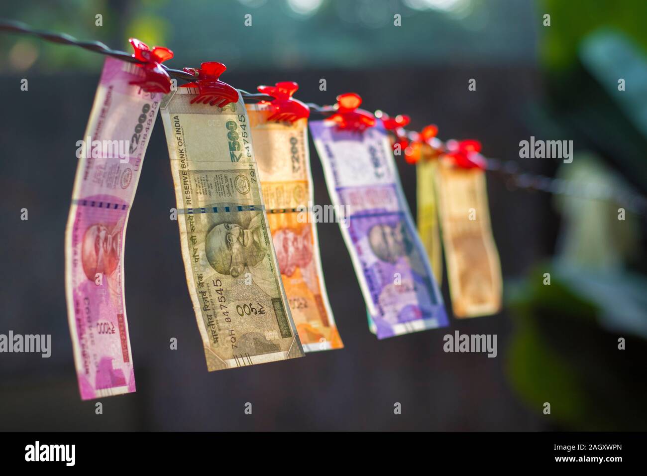 selective focus of new Indian currency notes rupees ten,twenty,fifty hundred,two hundred,five hundred and two thousand hanging in a wire. Stock Photo