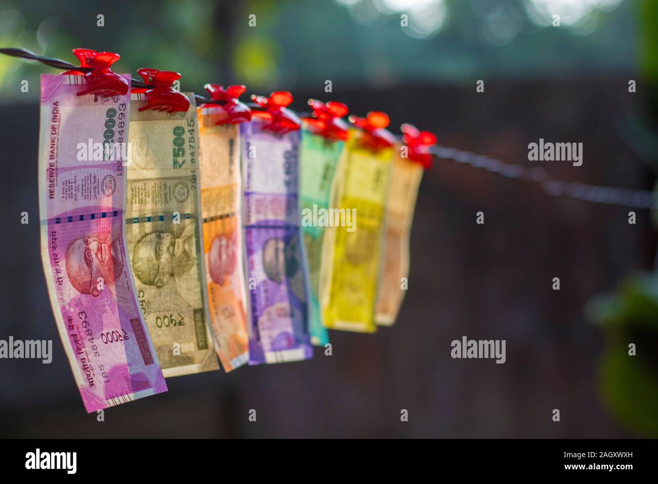 selective focus of new Indian currency notes rupees ten,twenty,fifty hundred,two hundred,five hundred and two thousand hanging in a wire. Stock Photo