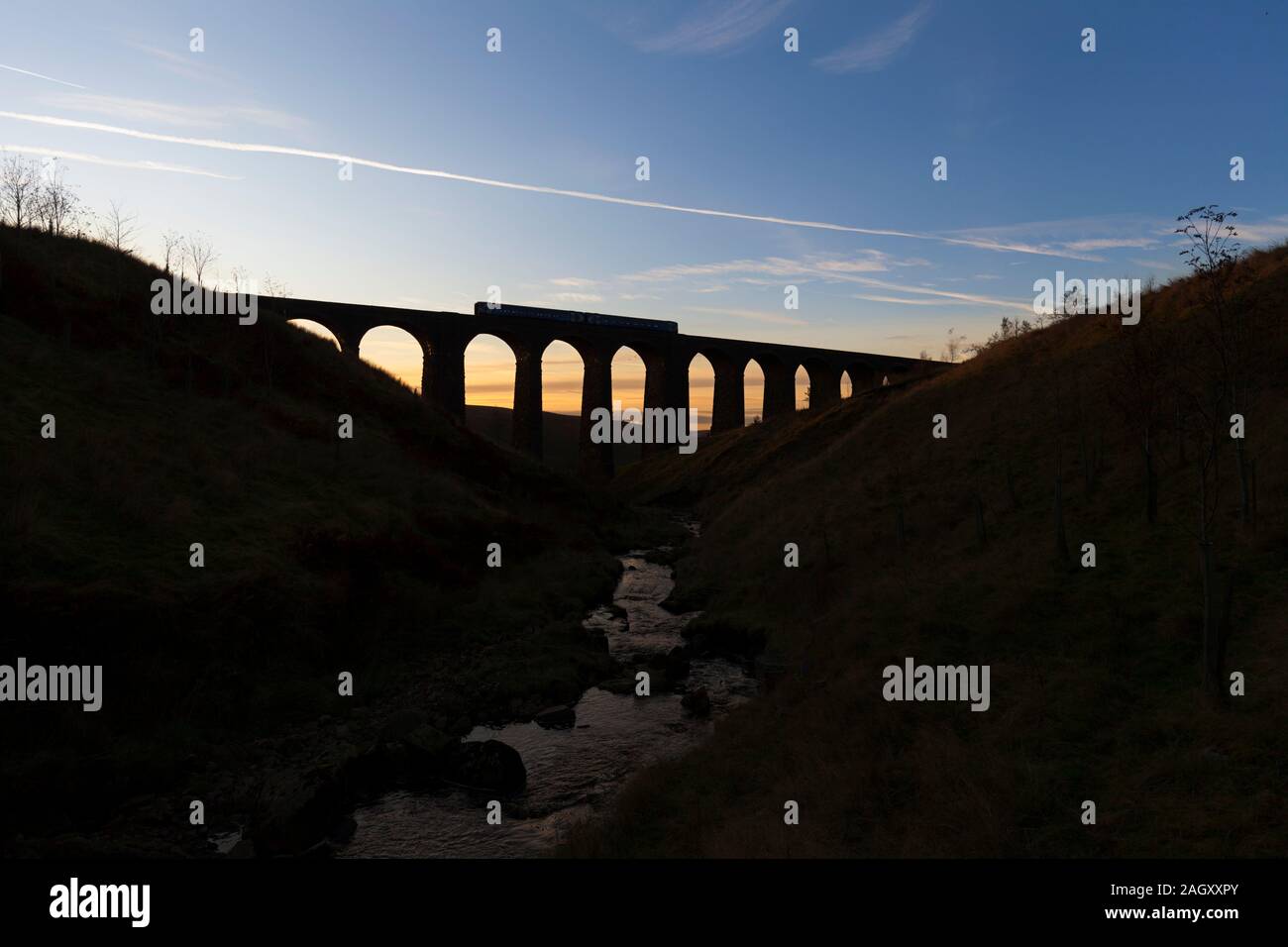 Arriva Northern rail class 158 sprinter train crossing Arten gill viaduct, on the Settle to Carlisle railway at sunset making a silhouette Stock Photo