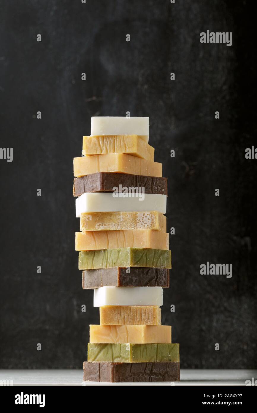 Tower stack of different kinds of handmade solid soap bars and shampoo over grey background Stock Photo