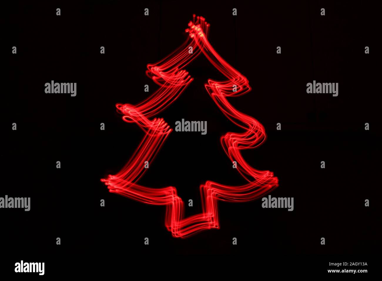 Light painting photograph of a festive christmas shape in red neon color against a black background. Long exposure photography. Stock Photo