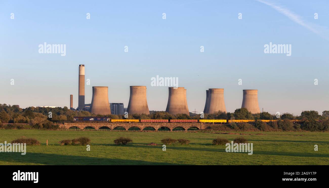 DRS  class 66 66421 locomotives passing Long  Eaton with a freight train carrying materials for Network Rail.  Ratcliffe power station behind Stock Photo