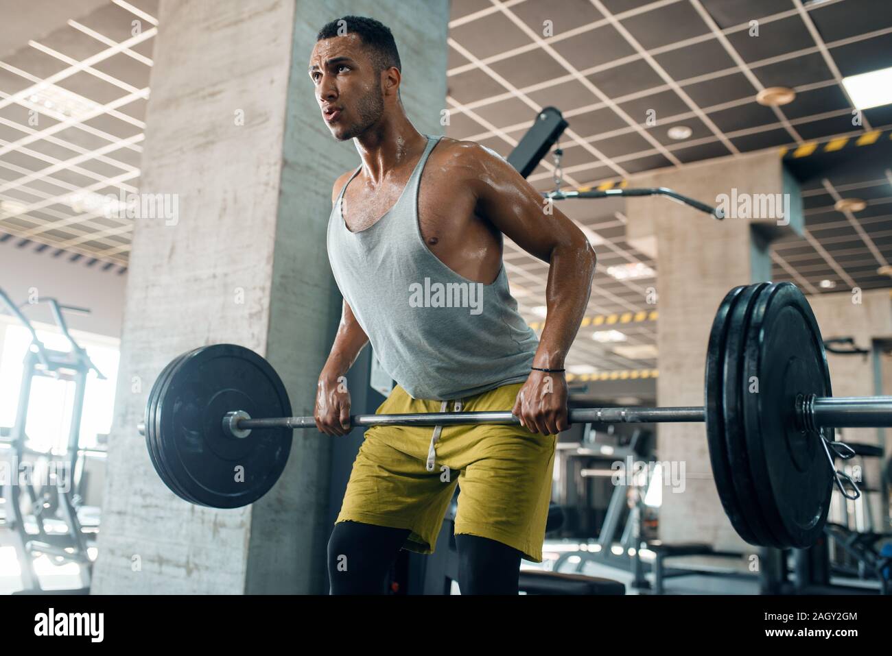Athletic man doing exercise with barbell in gym Stock Photo