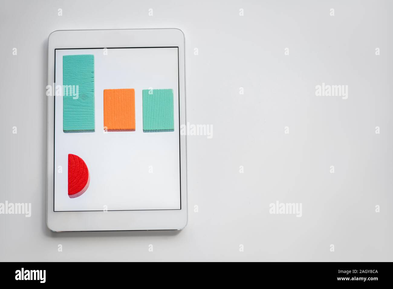 Colorful chart made up of flat wooden bricks lying in row on screen of tablet Stock Photo