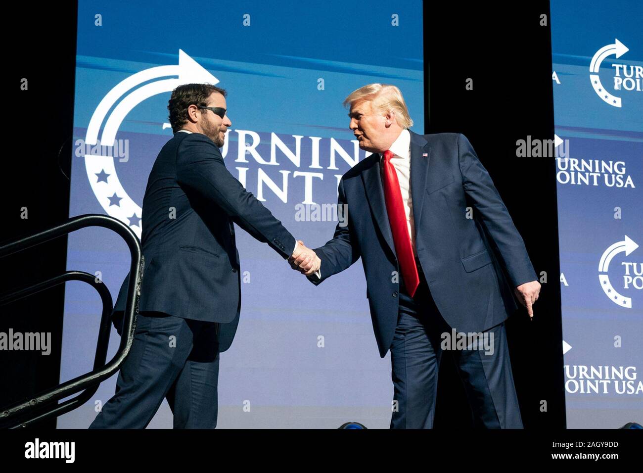 U.S President Donald Trump shakes hands with Texas Congressman Dan Crenshaw, at the Turning Point USA 5th annual Student Action Summit at the Palm Beach County Convention Center December 21, 2019 in West Palm Beach, Florida. Trump rallied the youth conservative group with wild claims on wind turbines and attacks on his opponents. Stock Photo