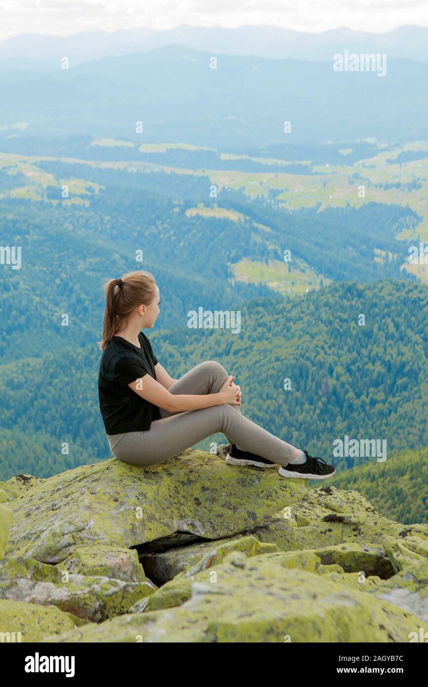 Young woman sitting on a rock and looking to the horizon Stock Photo ...