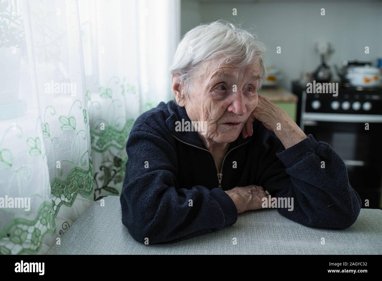 An old woman sitting in the kitchen of her apartment Stock Photo - Alamy