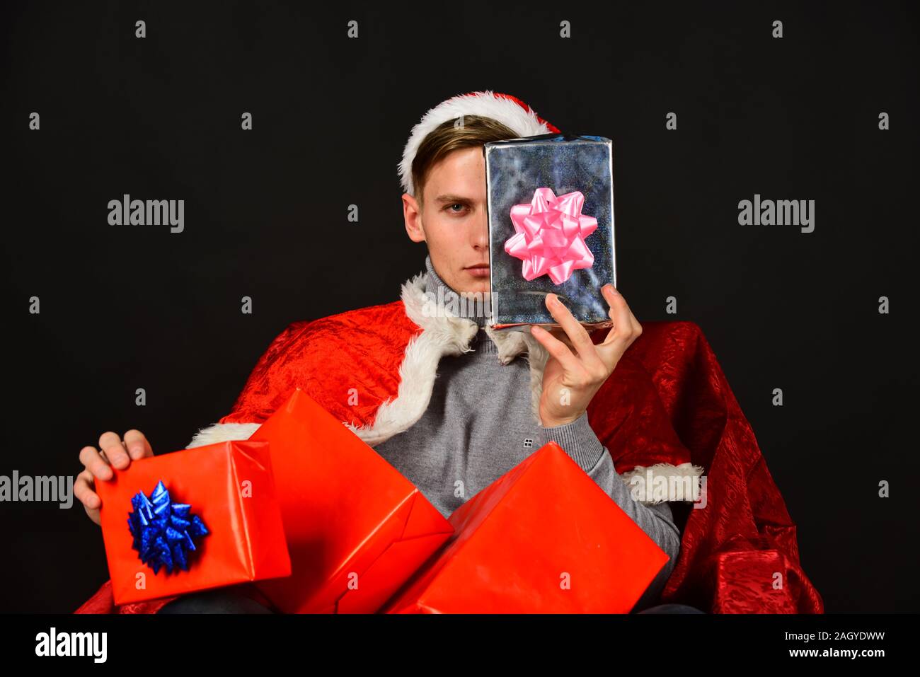Santa with presents on black background. Man shows half of face hiding
