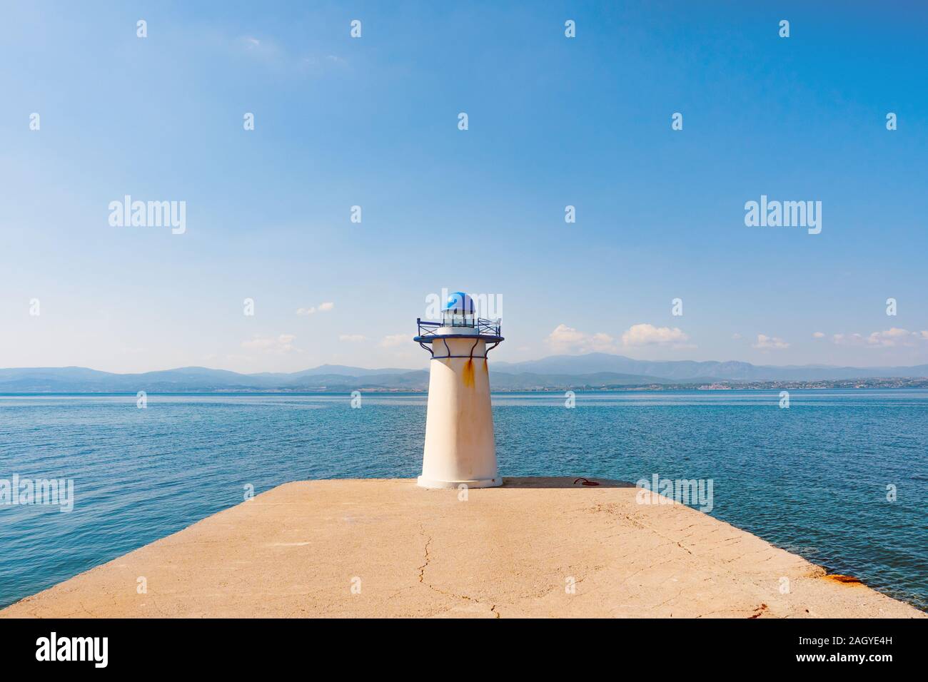 Lighthouse on clear sky background. Greek island with lighthouse. Nature with human artifact. Sea with clear sky on backdrop. Beacon, flashlight for water transport. Stock Photo