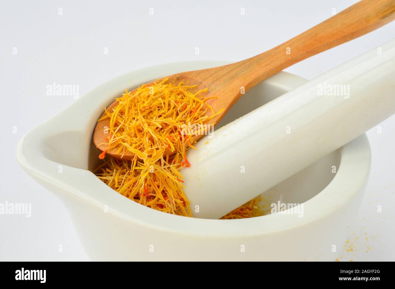 Saffron, tasty and costly spice in porcelain mortar and wooden teaspoon isolated on white background Stock Photo