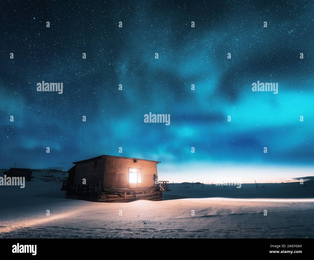 Aurora borealis over old small house with yellow light in window Stock ...