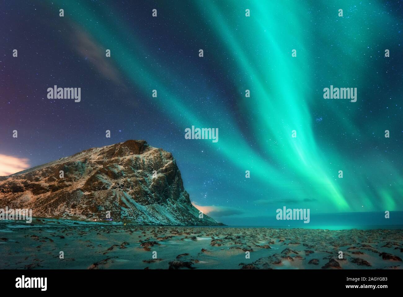 Aurora borealis above the snowy mountains and sandy beach Stock Photo