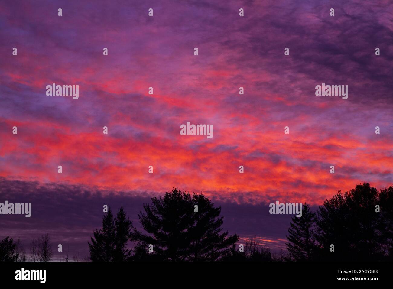 A cloudy red winter sky at sunset in Maine.  Beautiful and scenic. Stock Photo