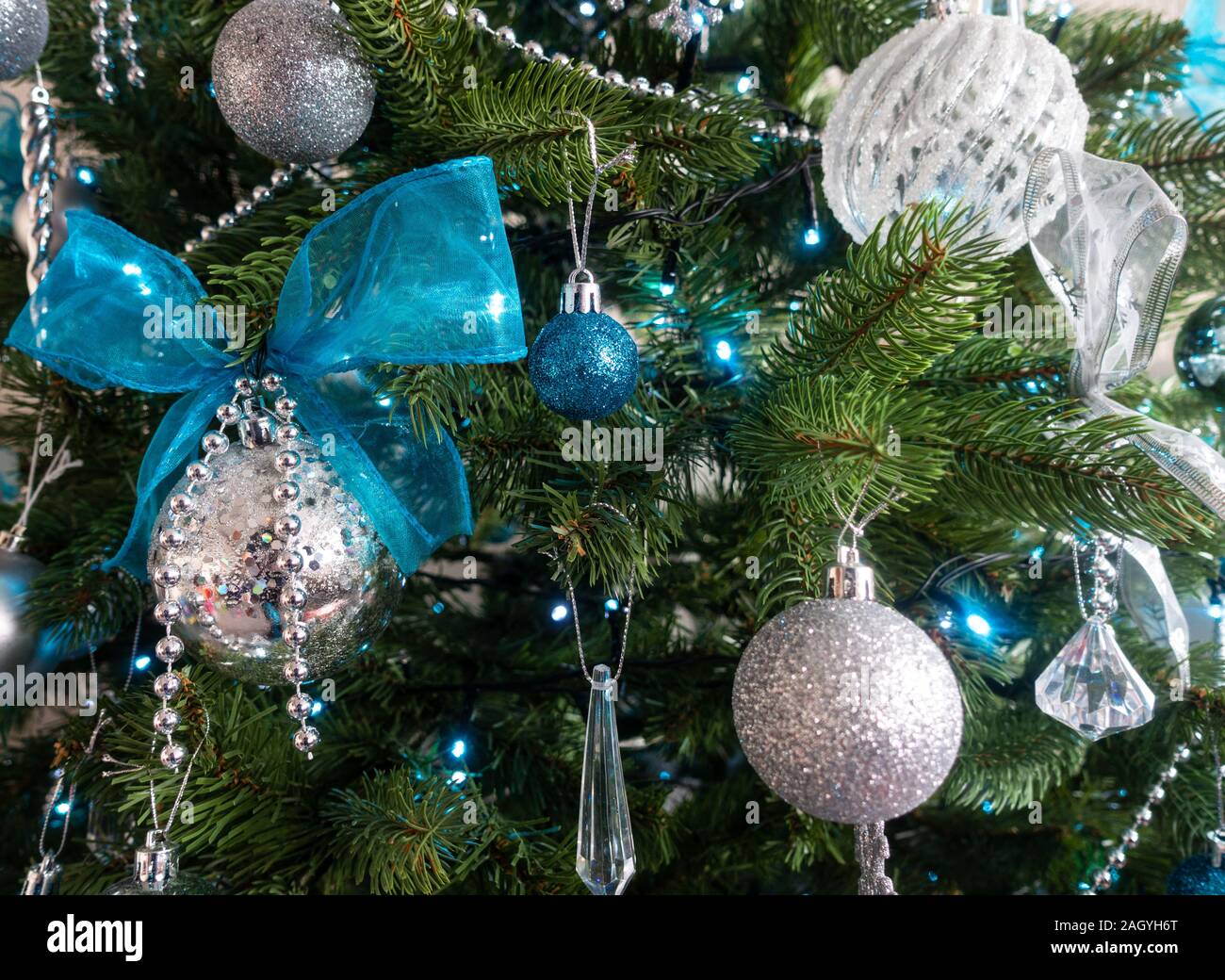 A Christmas tree decorated with silver and blue decorations. Stock Photo
