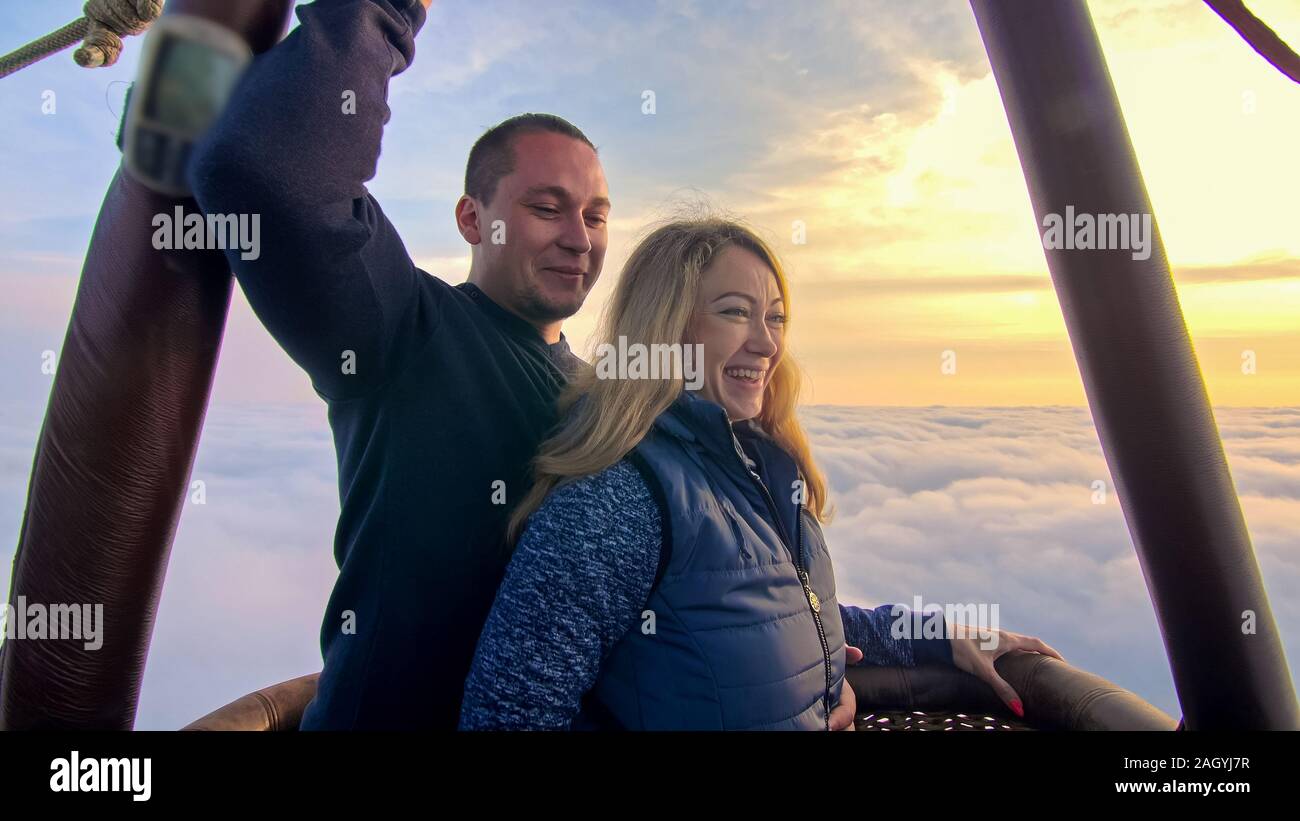 Adventure love couple on hot air balloon watermelon. Man and woman kiss hug love each other. Burner directing flame into envelope. Happy people. Stock Photo