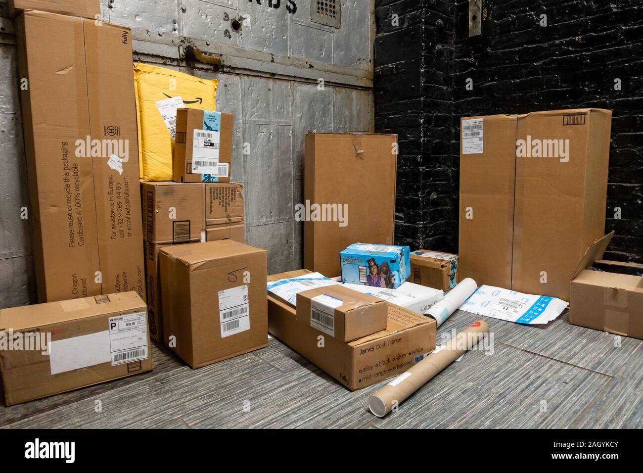 Amazon, FedEx and USPS other online shopping delivery packages stacked to be collected from an apartment mail room in Brooklyn, New York, USA Stock Photo