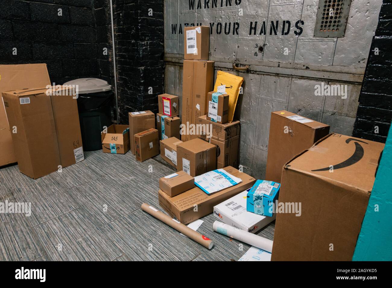 Amazon, FedEx and USPS other online shopping delivery packages stacked to be collected from an apartment mail room in Brooklyn, New York, USA Stock Photo