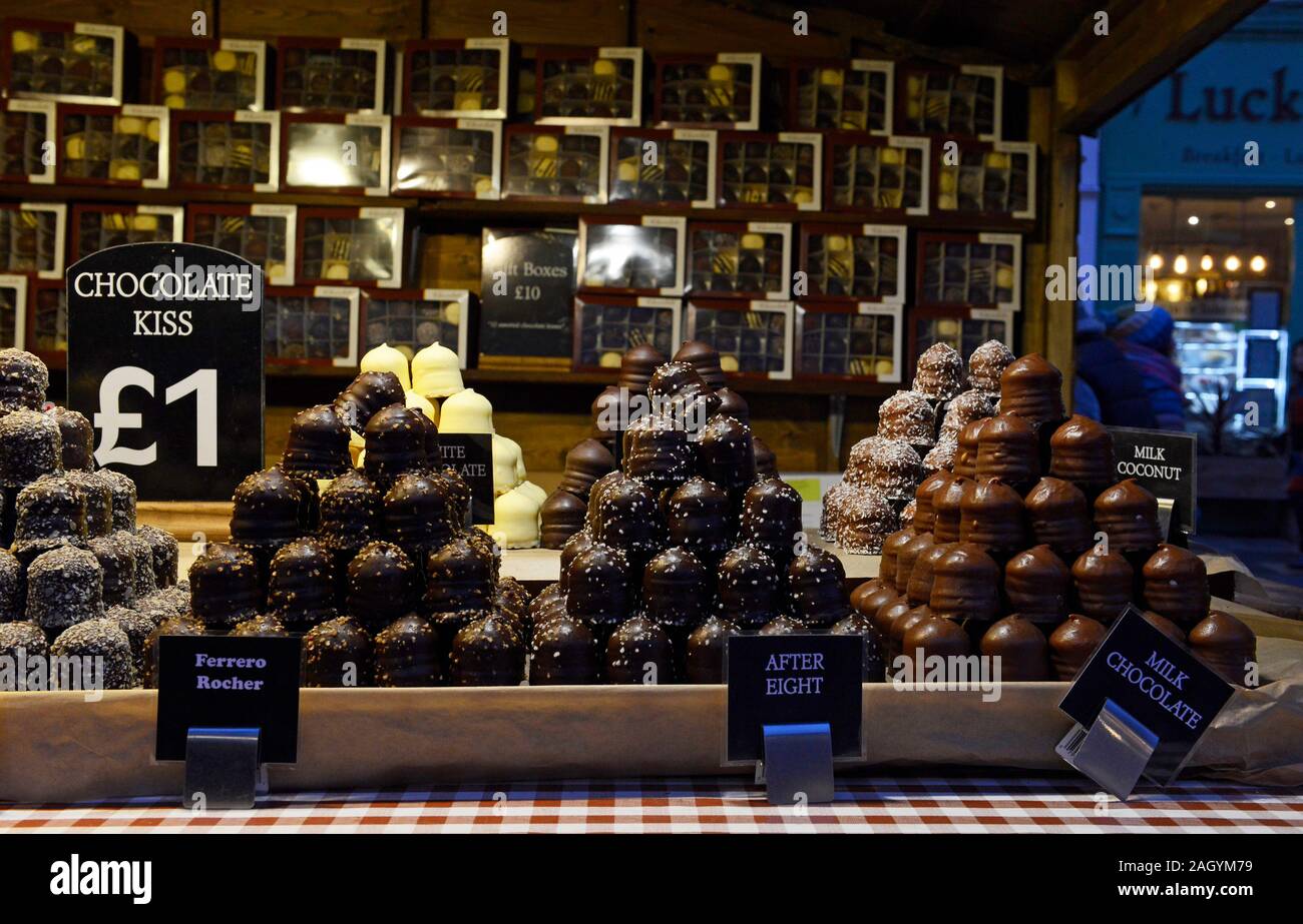 Pyramids of chocolates of different flavours on a stall at the Christmas market in York, UK, at dusk Stock Photo