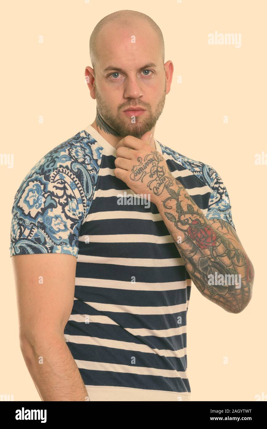 Studio shot of young bald muscular man with tattoos thinking Stock ...