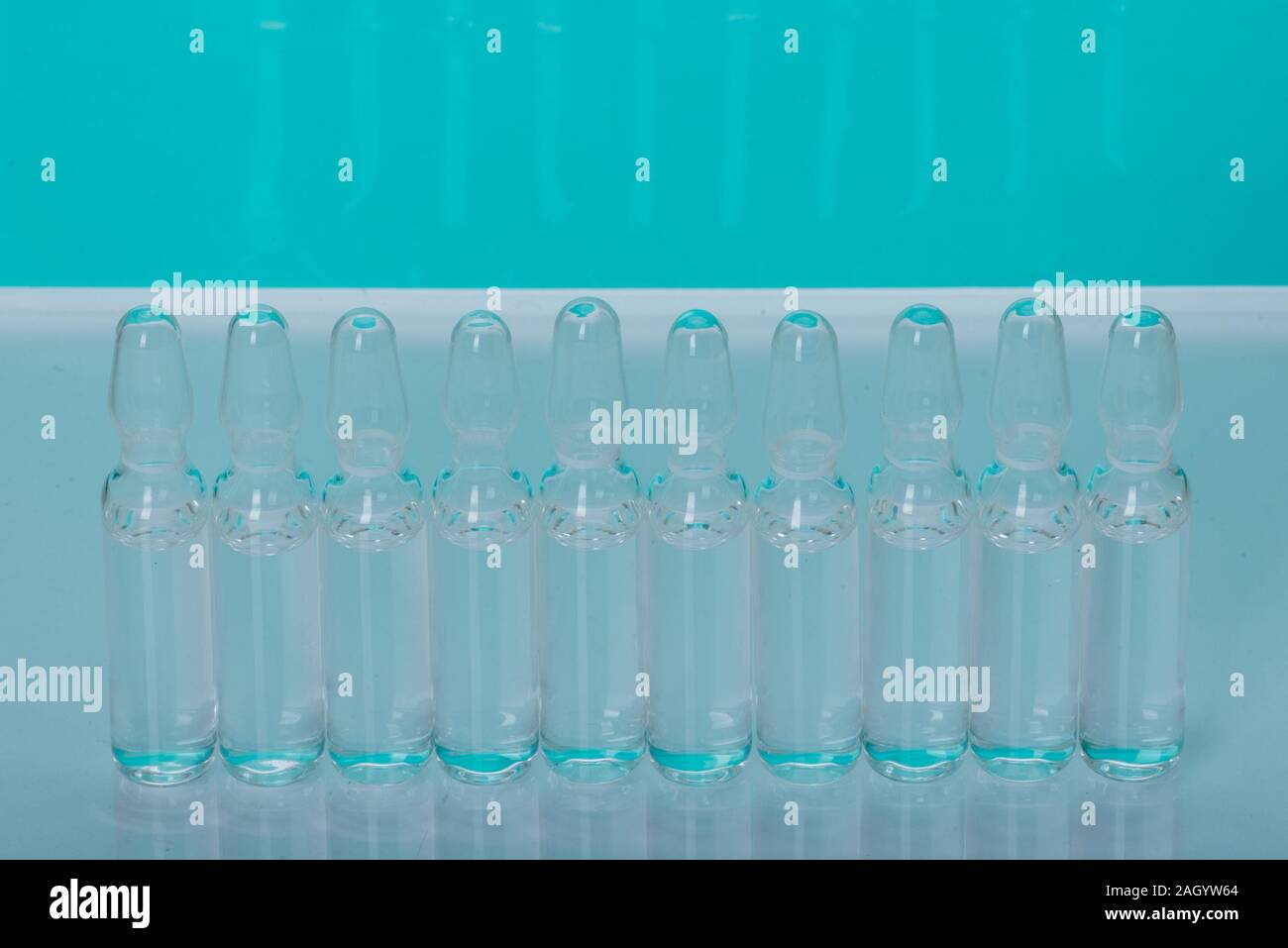 Glass medical ampoule vial for injection. Medicine is liquid sodium chloride with of aqueous solution in ampulla. Close up. Bottles ampule multicolor. Stock Photo