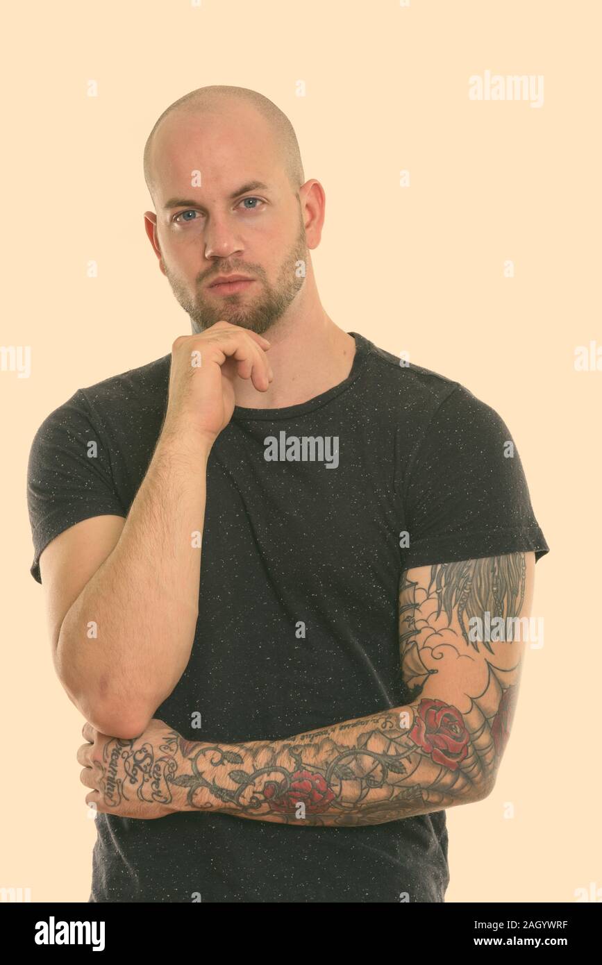 Studio shot of young bald muscular man with tattoos thinking Stock ...