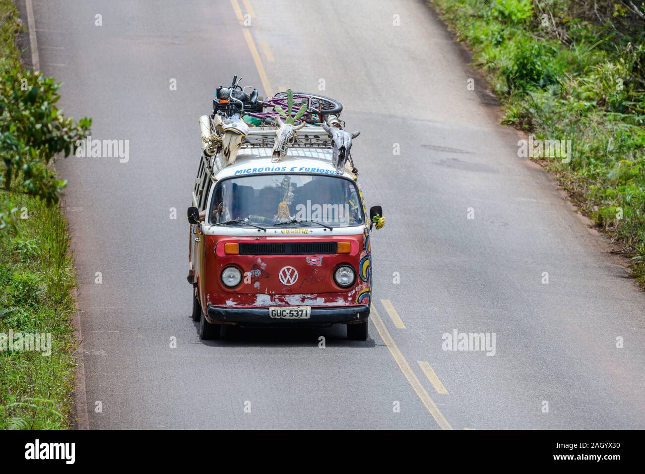 A highly decorated red VW mini bus going down the highway at Chapada Diamantina, Bahia, Brazil. Stock Photo