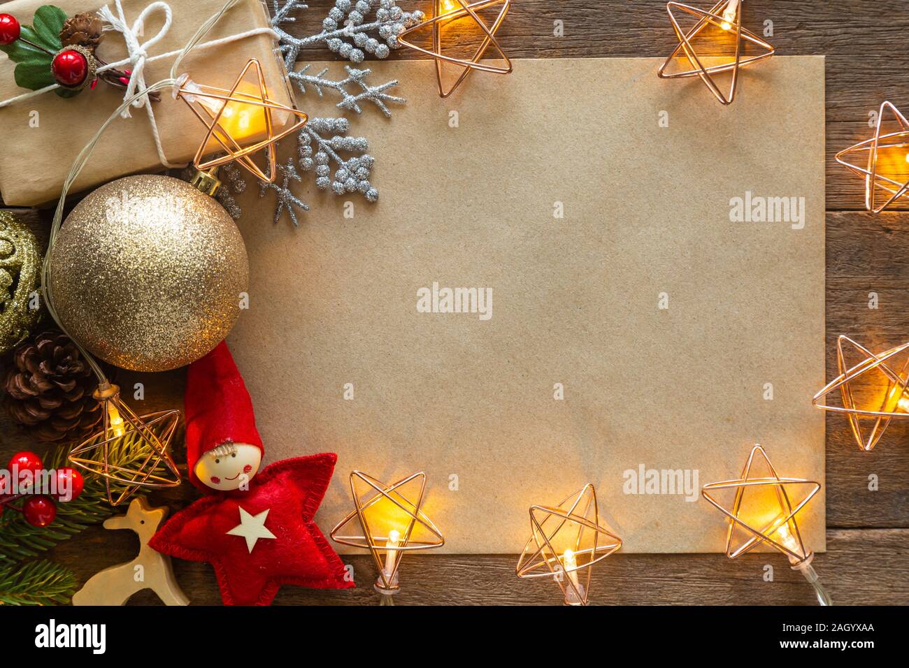 Holiday Christmas card background with festive decoration ball, stars, snowflakes, gift box, pine cones on a wood background from Flat lay, top view. Stock Photo