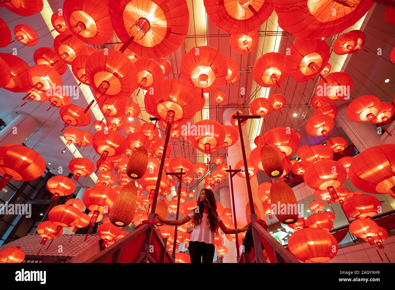 Woman walking and enjoying traditional red lanterns decorated for Chinese new year Chunjie. Asian culture inspiration. Trend lava color. Stock Photo