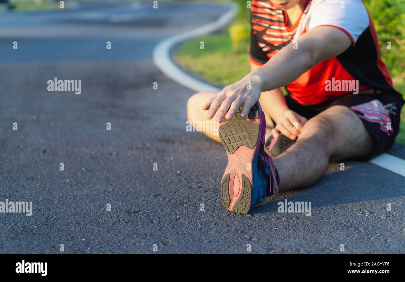 athlete man stretching his legs or calf muscle before exercising and running. Sport and exercise concept. Stock Photo