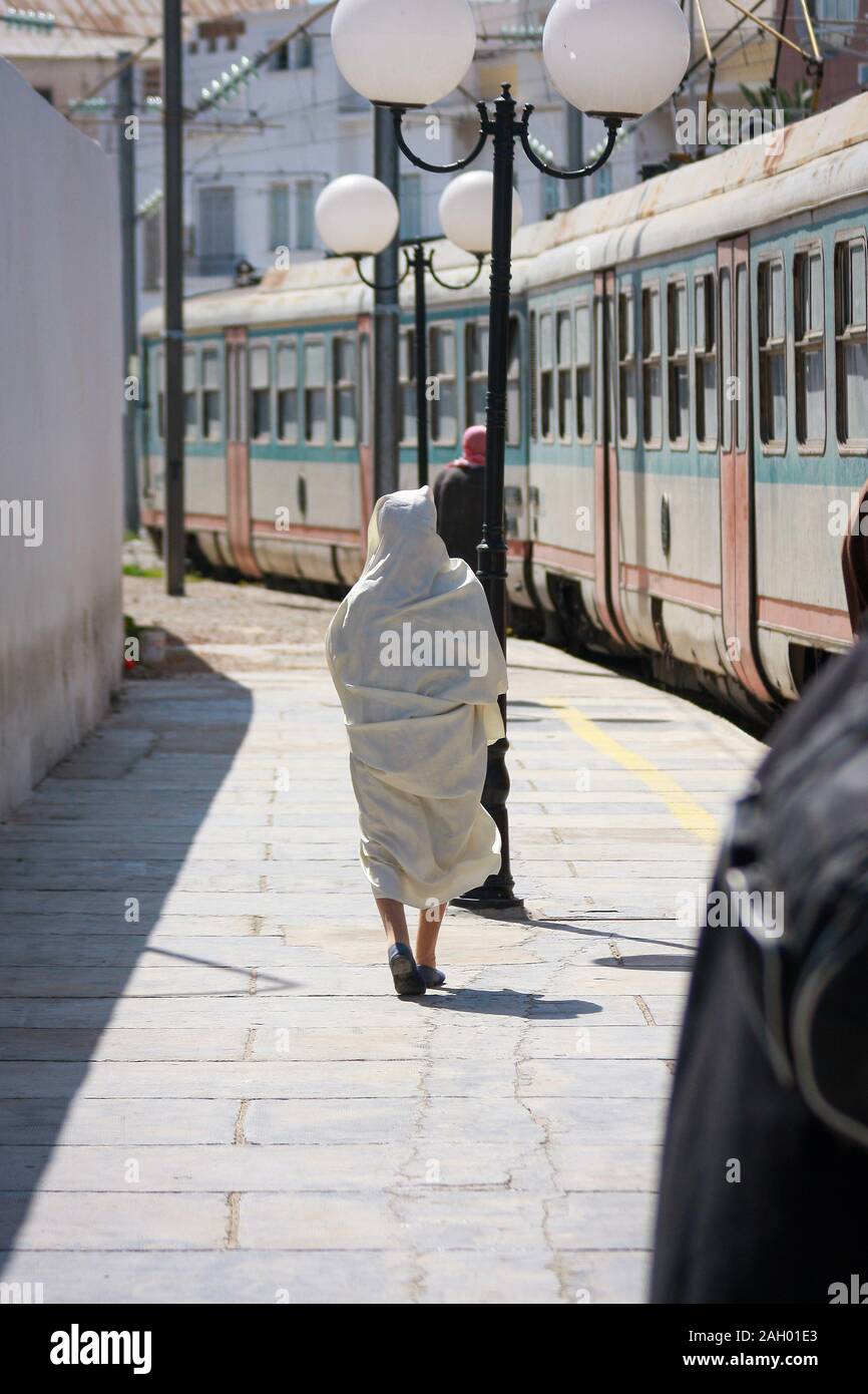 A woman dressed in a white robe, catching a train at the Train Station of  Sousse, Tunisia Stock Photo - Alamy