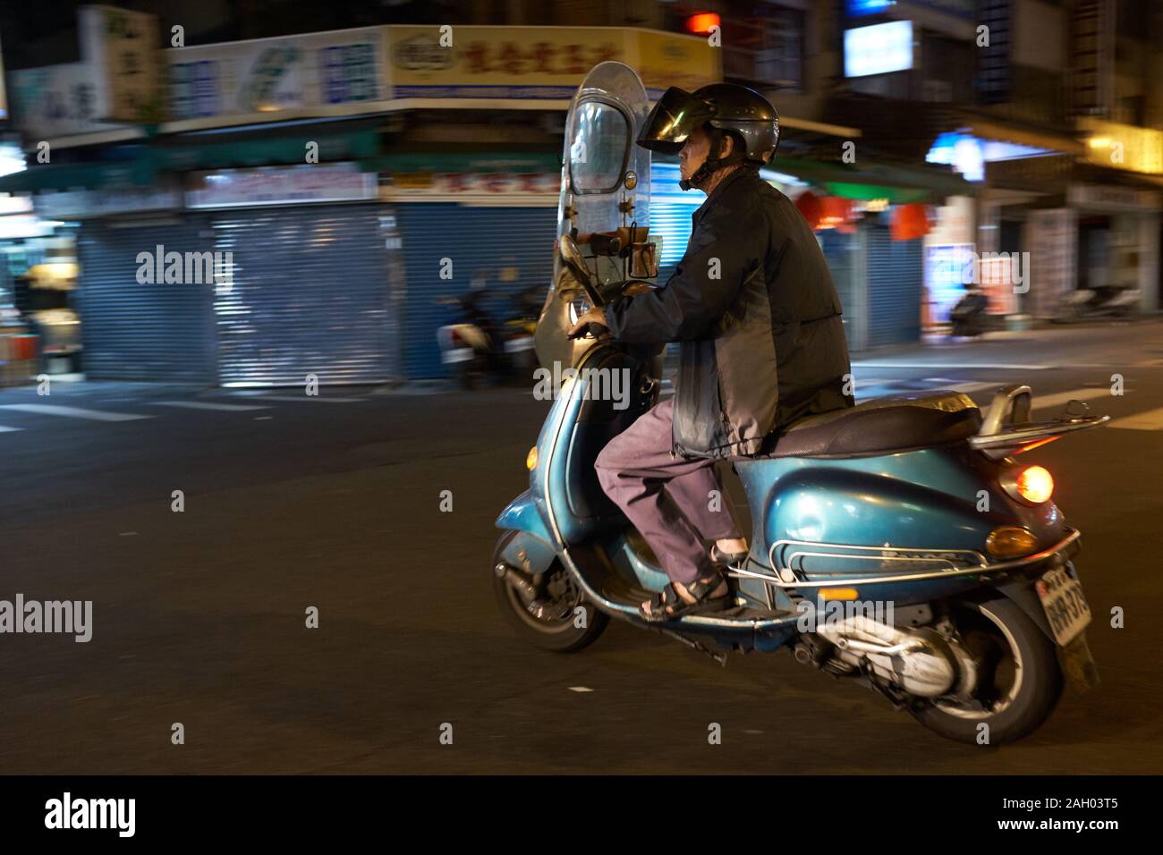 Man Riding Motor Scooter at Night, Taipei, Taiwan Stock Photo