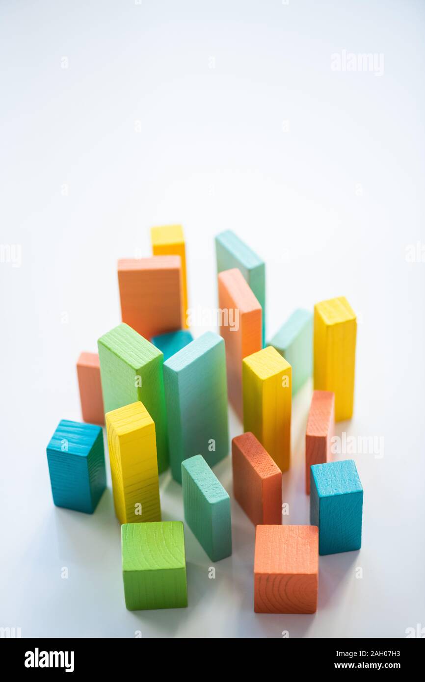 Blue, orange, yellow and green flat wooden bricks and cubes making up chart in isolation with copyspace above Stock Photo