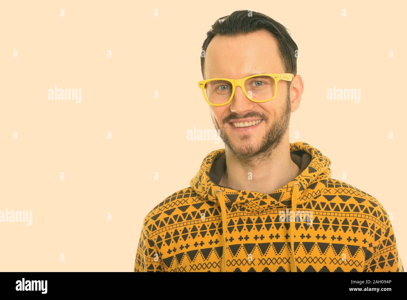 Studio shot of happy young man smiling while wearing yellow eyeglasses Stock Photo