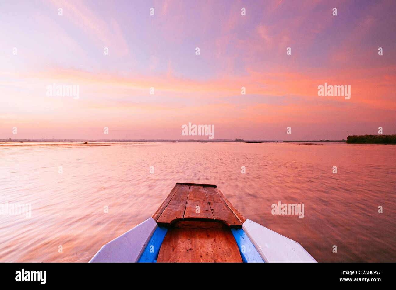 Thai long tail boat front bow in peaceful Nong Harn lake, Udonthani - Thailand. Wooden boat under beautiful blue morning sky over red lotus lake. Stock Photo