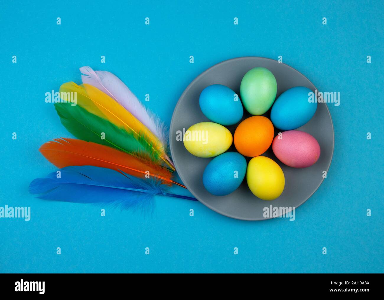 Easter multi-colored eggs and feathers on blue background. Stock Photo