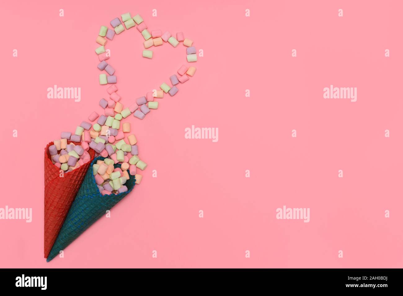 Waffle cone with heart-shaped marshmallows, close-up on a blue wooden  background. Stock Photo by puhimec