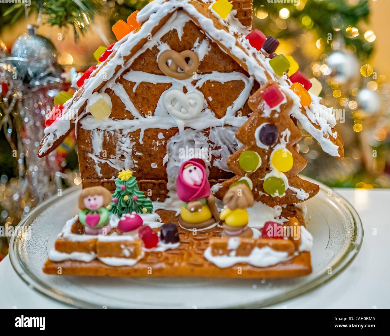 Selective focus on homemade and home decorated ginger bread house with soft focus sugar candy characters out front on a white table Stock Photo