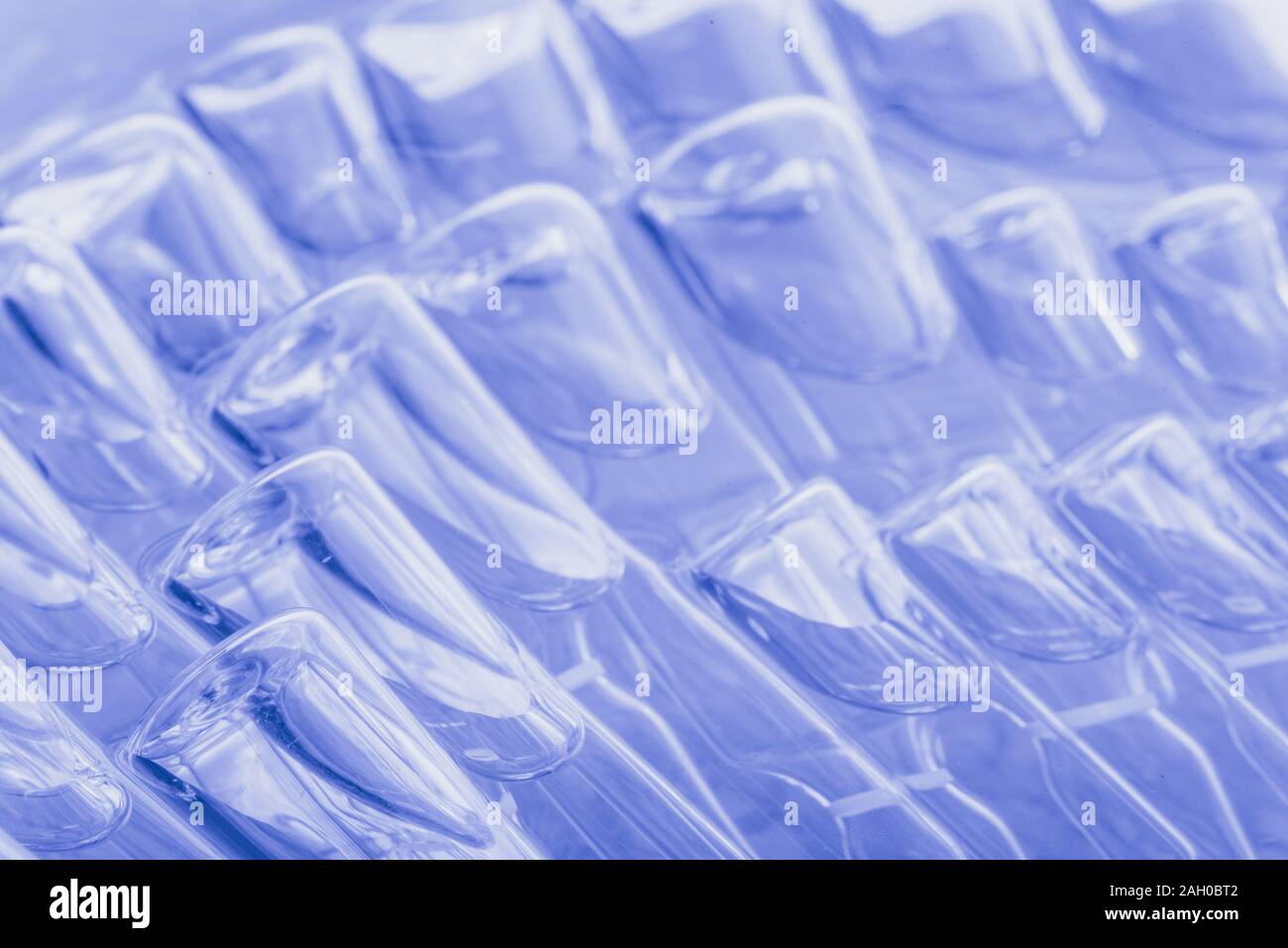 Glass medical ampoule vial for injection. Medicine is liquid sodium chloride with of aqueous solution in ampulla. Close up. Bottles ampule multicolor. Stock Photo