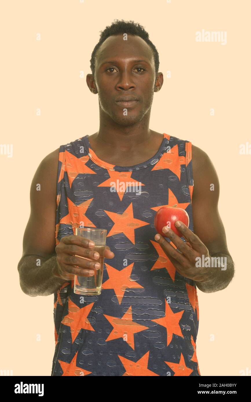 Young black African man holding glass of water and red apple Stock ...