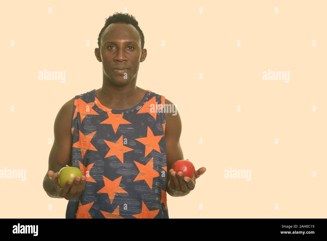 Young black African man holding green and red apple Stock Photo - Alamy
