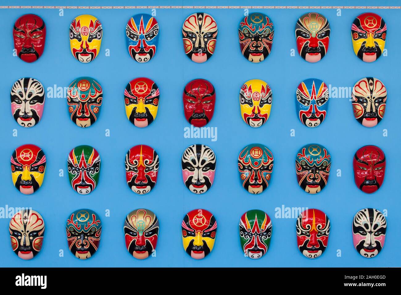Colourful hand painted Chinese opera masks hang up neatly on a