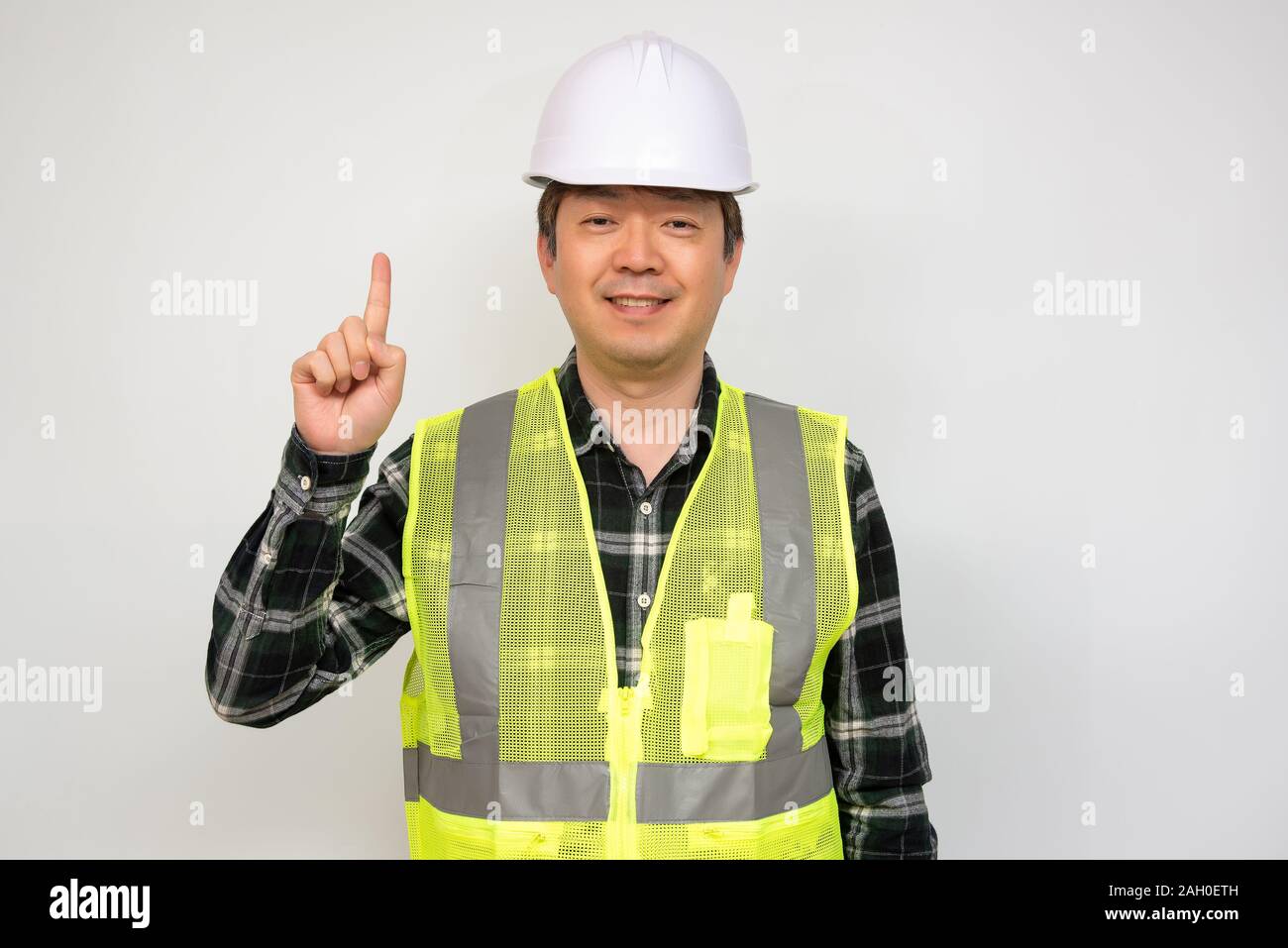 Asian middle-aged man in a Light green work vest and white safety hat. Stock Photo