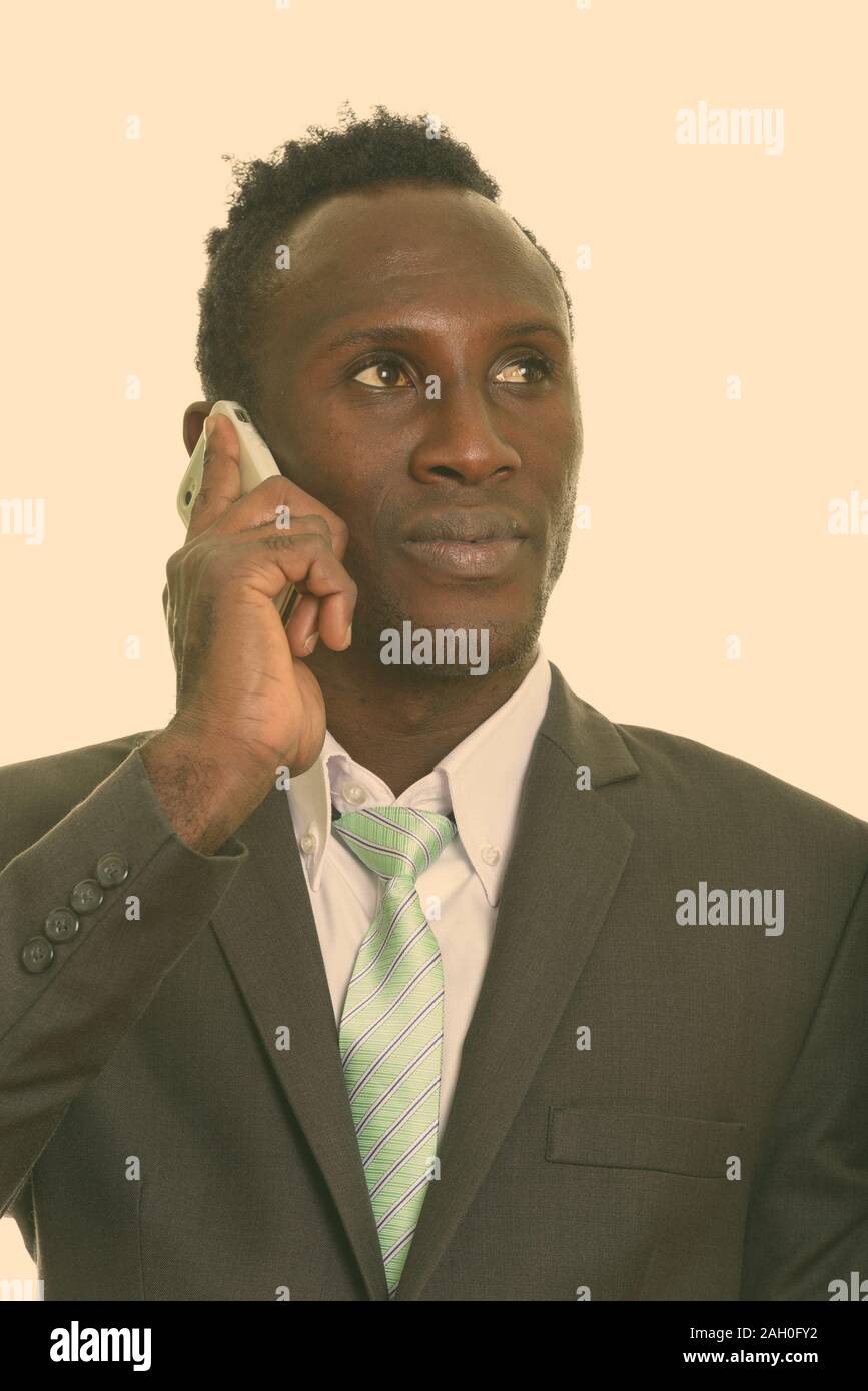 Face of young black African businessman talking on mobile phone while thinking Stock Photo