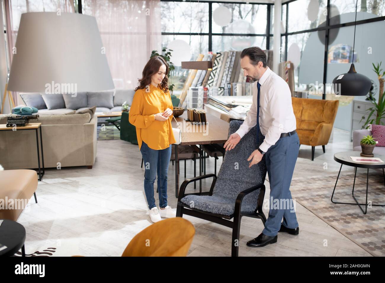 Manager in tie and white shirt showing armchair to the customer Stock Photo Alamy