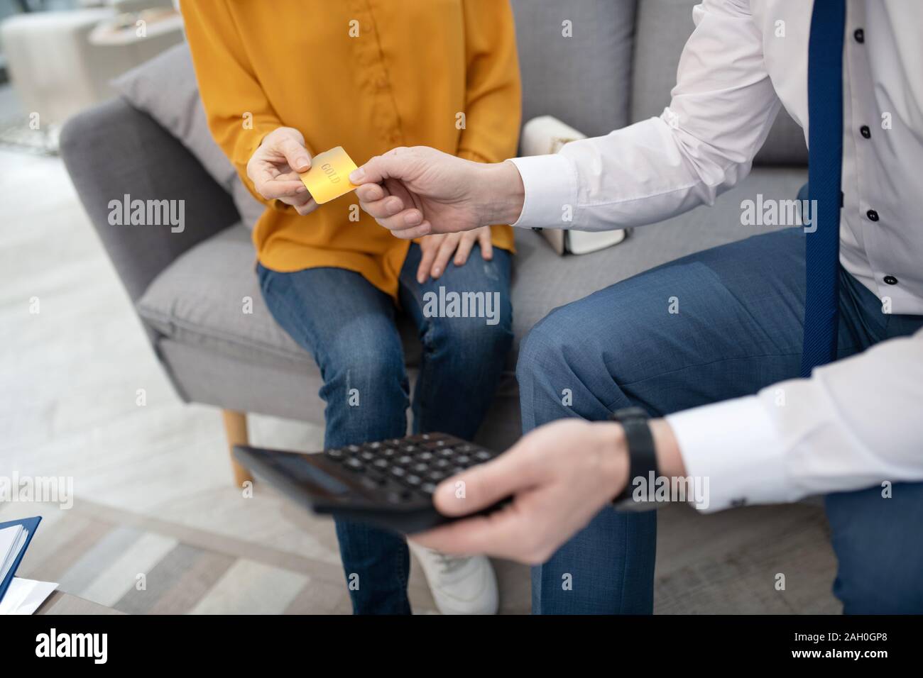 Customer in yellow shirt giving credit card to manager Stock Photo - Alamy
